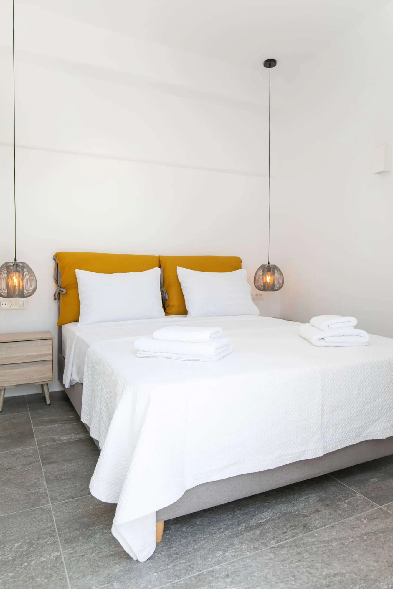 Junior Garden Suite · Queen bed with ochre cushions and wire pendant lamp